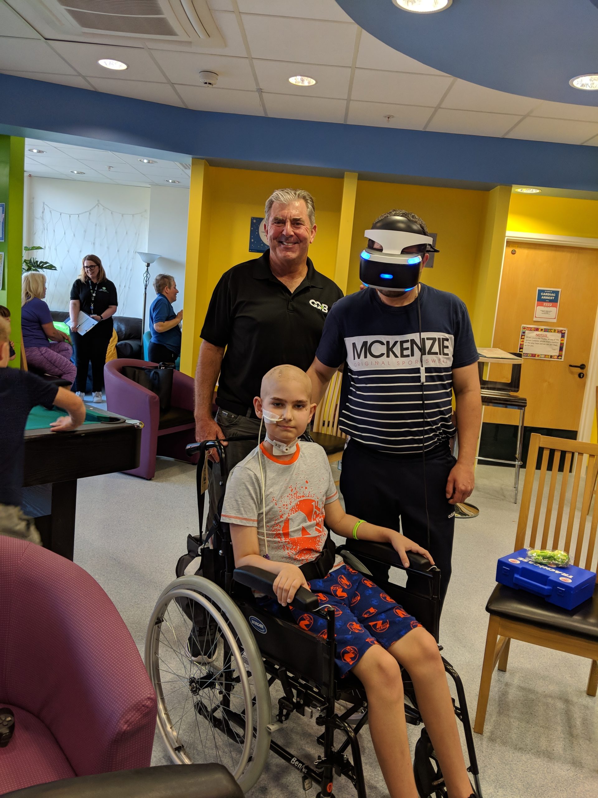 A patient and parent sharing a virtual-reality headset in a hospital game room