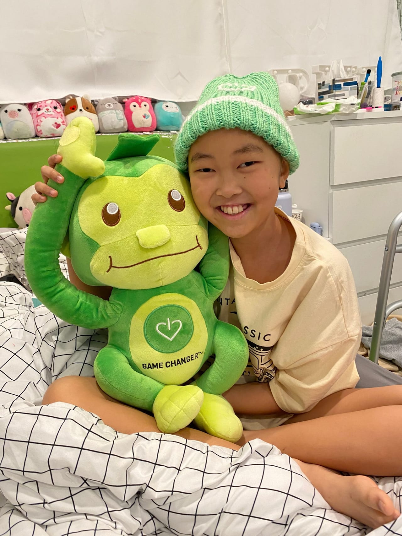 A young patient smiling with Hope the Monkey, a GameChanger comfort gift